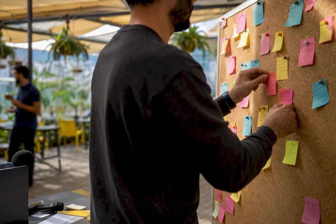Hands organizing bug report notes on glass wall